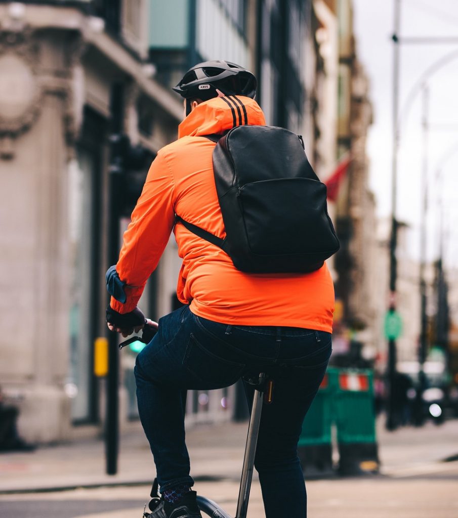 A cycling commuter in an orange jacket.