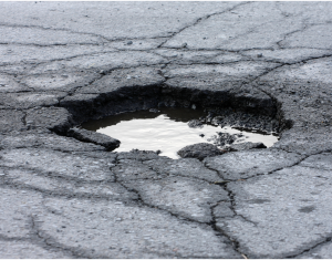 A large pothole in the road, filled with water.